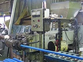青い樹脂パイプが押出成形機から送り出される工場の加工ライン